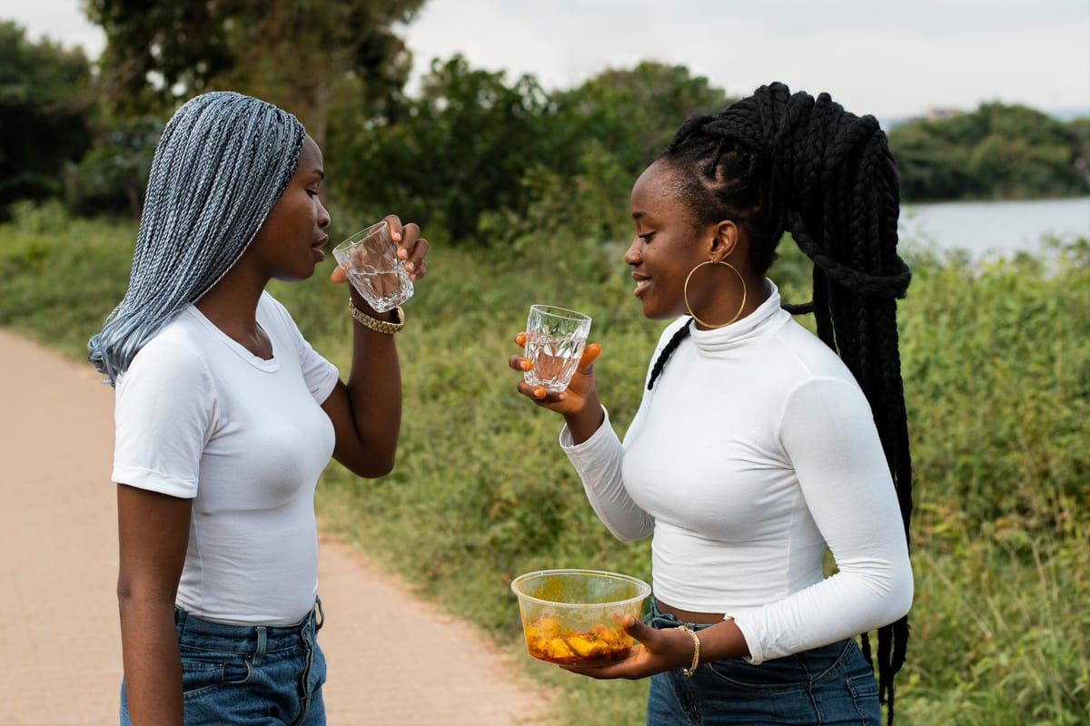 Two women collecting water from an open source