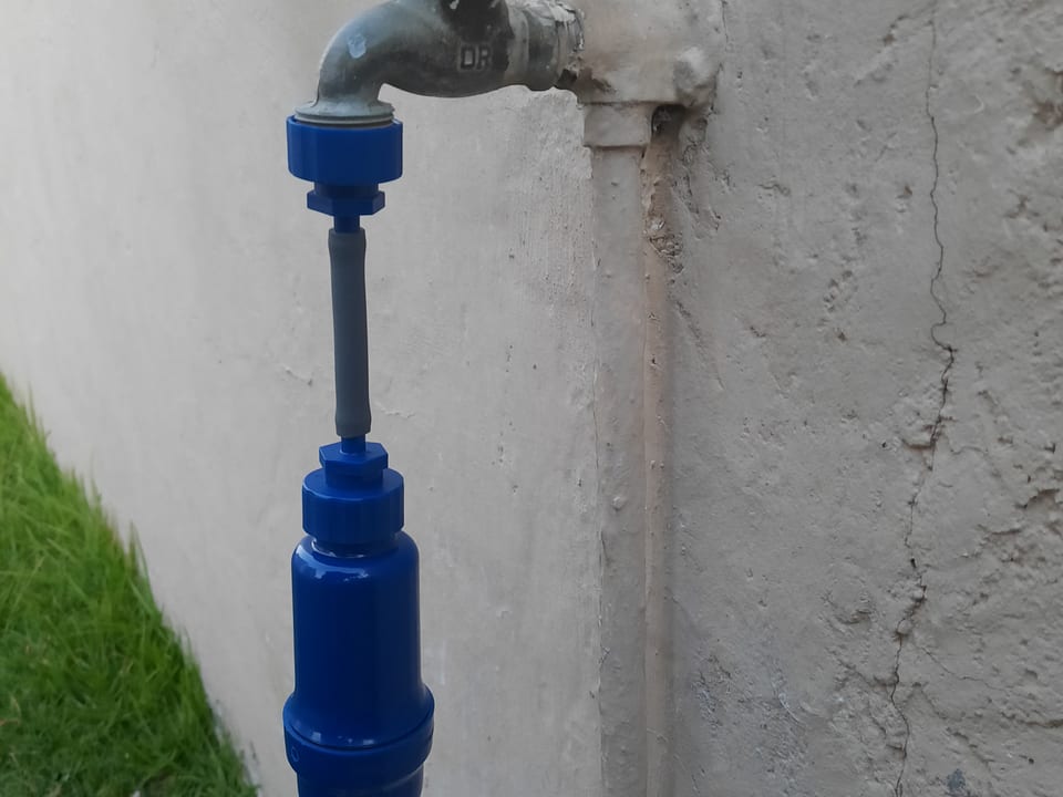The filter connected to an outdoor garden tap, water running clear